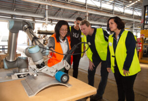 Image of Engineers showing robotic arm to researchers